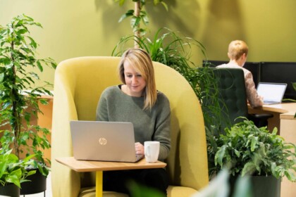 Woman using a laptop within a contemporary workplace environment featuring integrated interior planting.