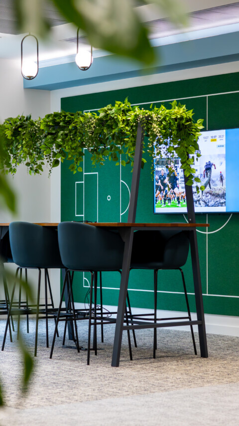 Modern open-plan office featuring framed desk workstations with suspended planting integrated above.