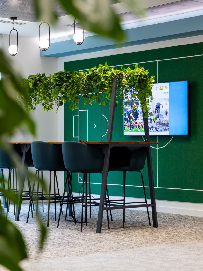Modern open-plan office featuring framed desk workstations with suspended planting integrated above.