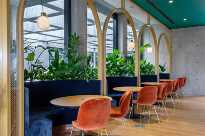 Modern workplace lunch area featuring tables, chairs, and integrated interior planting.