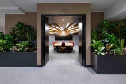 Modern office interior doorway with large planting arrangements positioned on either side.