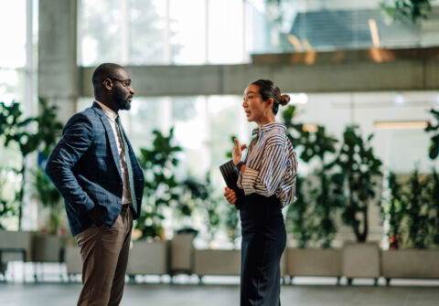 Businesspeople Talking In Modern Office Building Lobby