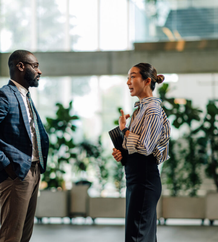 Businesspeople Talking In Modern Office Building Lobby