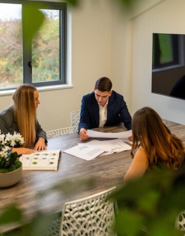 Exubia business development and design team discussing a planting project around an office meeting table.