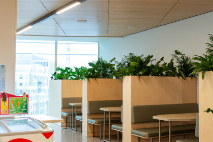 Alternative-angle view of modern office booths featuring integrated planting within each seating area.